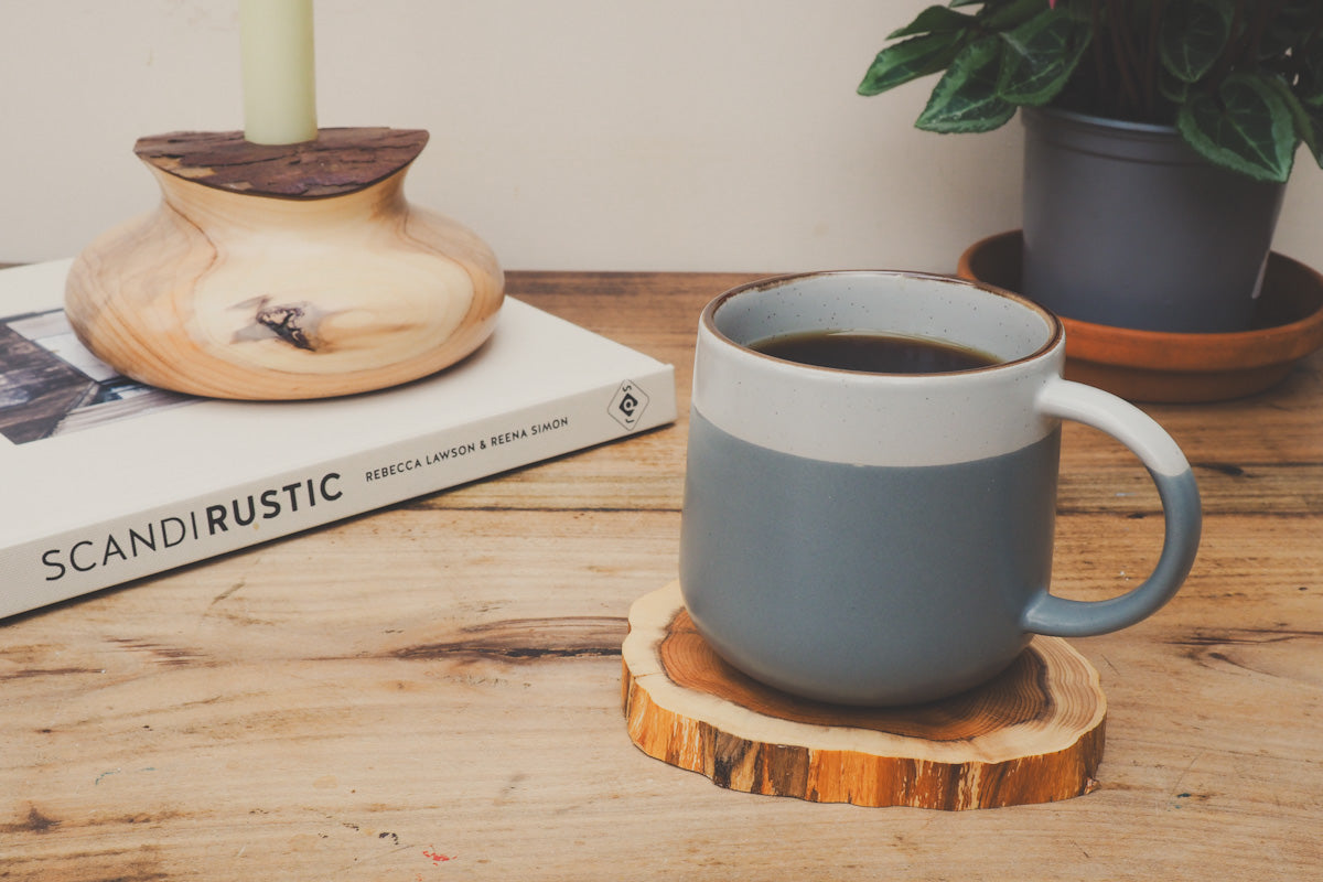 Scandi style mug on a wooden yew coaster with a book called Scandi Rustic and a handturned candle holder