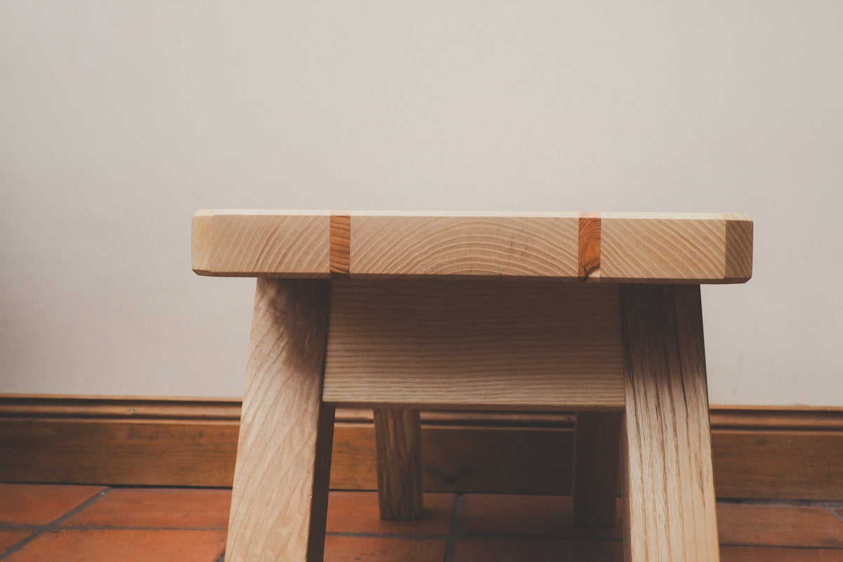 The Northumberland stool viewed from the side with two contrasting stripes on the top.